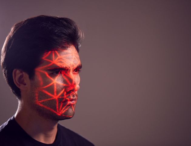 Facial Recognition Technology Concept As Man Has Red Grid Projected Onto Face In Studio